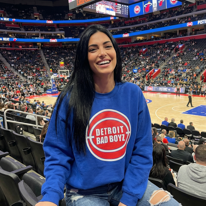 Pretty Woman wearing a blue Bad Boyz crewneck sweatshirt by Ink Detroit enjoying a game at LCA.